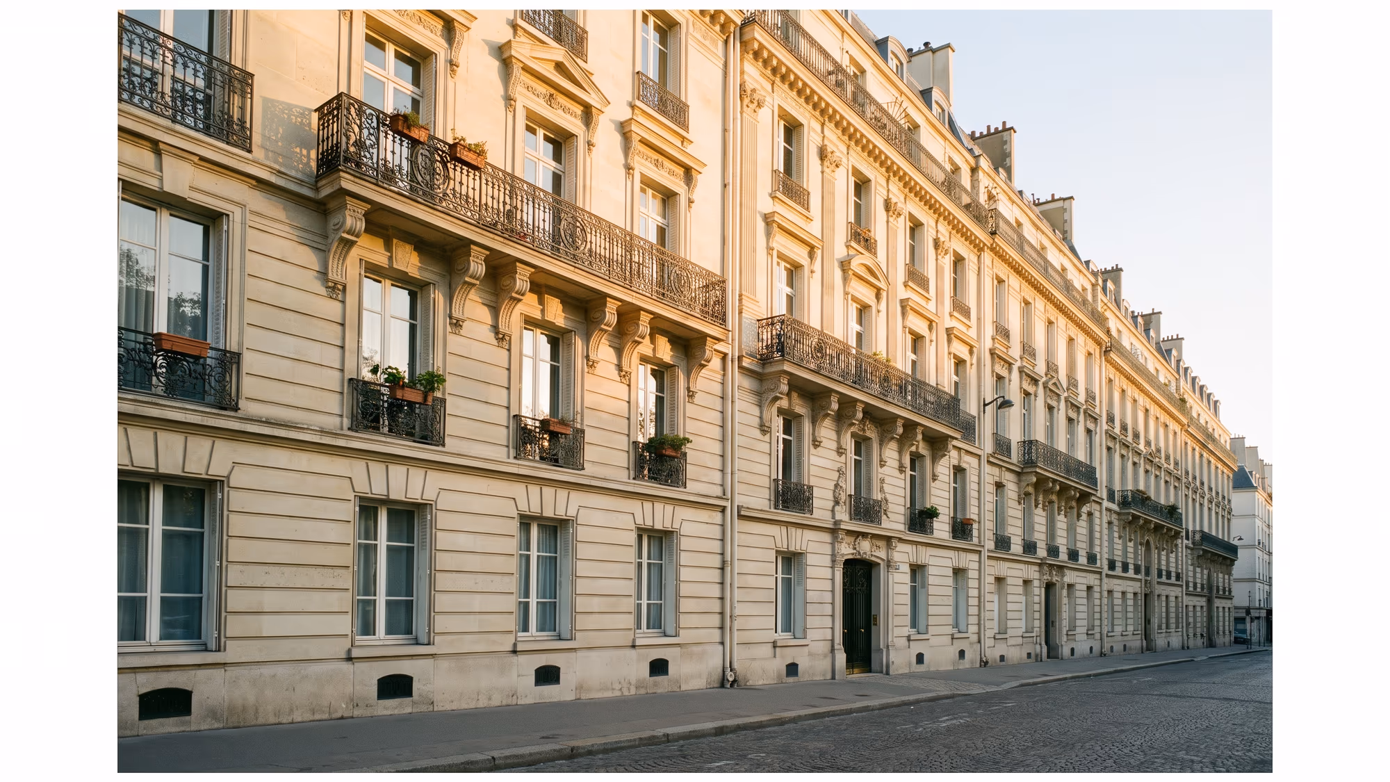 Façade d'immeuble en pierre de taille au soleil couchant avec balcons en fer forgé